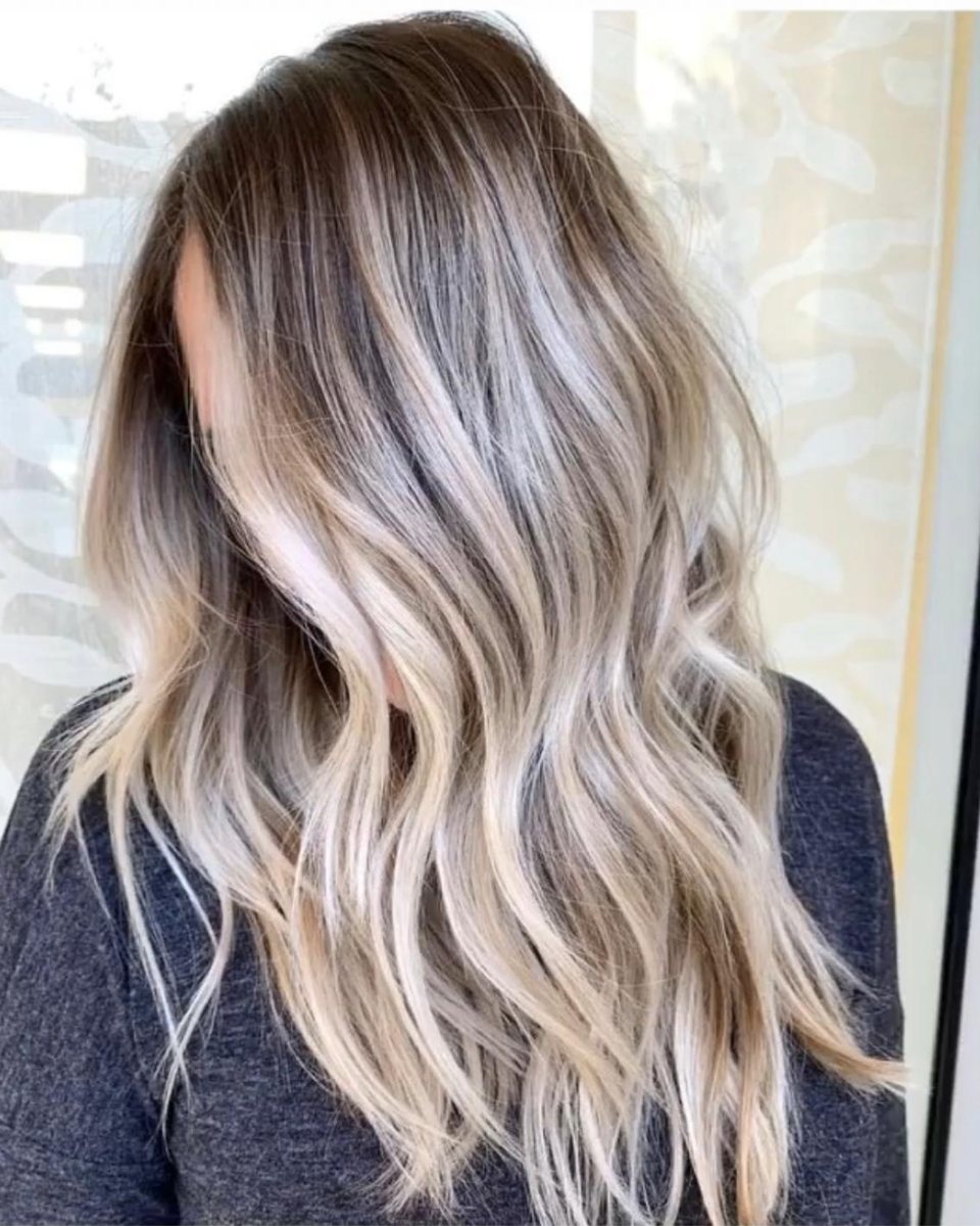 Résultat balayage au salon : blond fondu aux reflets lumineux sur cheveux longs ondulés