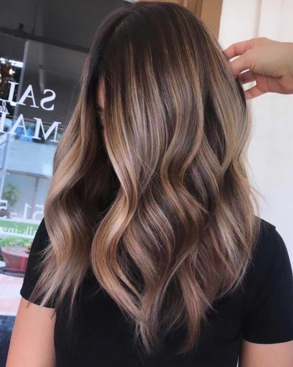 Balayage caramel fondu sur base châtain, cheveux longs ondulés